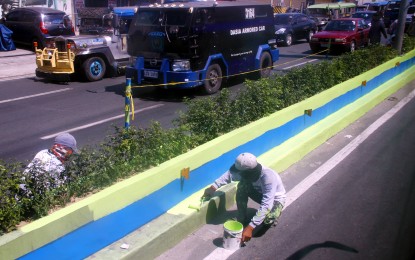 Worker paint center island along Aguinaldo Highway