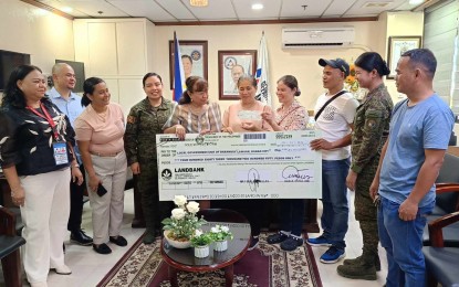 <p><strong>LIVELIHOOD FOR EX-REBELS.</strong> Flor Lingues (center), the head of the Lawaan Farmers and Livestock Association in the mountain village of Lawaan in Danao City, Cebu, holds a check worth PHP483,000 that would help them start their hog-raising project. With Lingues are DOLE-7 Regional Director Lilia Estillore (4th from left) and other DOLE-7 and 3rd Civil Relations Group officials. <em>(Photo courtesy of the Philippine Army's 3rd Civil Relations Group) </em></p>