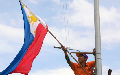 <p><strong>NATIONAL PRIDE.</strong> A local government worker hangs a Philippine flag from one of the steel posts of Navotas Bridge in Navotas City on Monday (May 27, 2024). The National Flag Days from May 28 to June 12 commemorate the first unfurling of the Philippine flag in Cavite in 1898, leading to the declaration of independence from Spain.<em> (PNA photo by Yancy Lim)</em></p>