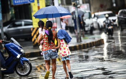 <p><strong>SEASON CHANGE.</strong> A mother and her two children cross the intersection of Kamuning Road and EDSA, Quezon City on Wednesday (May 29, 2024). State weather bureau PAGASA has declared the start of the wet season following significant rainfall the past few days over the western sections of Luzon and Visayas, frequent thunderstorms and Typhoon Aghon.<em> (PNA photo by Joan Bondoc)</em></p>