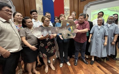 <p><strong>CEREMONIAL TURNOVER.</strong> Dumaguete City Mayor Felipe Antonio Remollo (in maroon polo shirt) on Wednesday (May 29, 2024) turns over a "key" to Department of Education (DepEd) City Schools Division Supt. Marina Salamanca (in black dress with flower prints) for the new site of two public elementary schools in Dumaguete City, Negros Oriental. The city government and the Ursuline Sisters of Somac signed a purchase agreement for the sale of the former Catherina Cittadini - St. Louis School, which closed last year. <em>(PNA photo by Mary Judaline F. Partlow)</em></p>