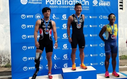 <p><strong>PODIUM FINISHERS.</strong> Paralympian Jiachao Wang of China (center) won the men's PTS4 category of the NTT Asia Triathlon Para Championships at the Subic Bay Freeport Zone in Olongapo City on Sunday (June 2, 2024). With him are silver medalist Keiya Kaneko of Japan (left) and bronze medalist Alex Niño Silverio of the Philippines.<em> (PNA photo by Jean Malanum)</em></p>