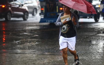 <p><strong>KEEPING THEM DRY.</strong> A pedestrian clutches his documents and mobile phone to protect them from the heavy downpour, while passing along EDSA-Kamuning Road in Quezon City on June 21, 2024. The easterlies and the southwest monsoon or habagat will bring rain showers in most parts of the country on Monday (June 24, 2024), the weather bureau said. <em>(PNA photo by Joan Bondoc)</em></p>