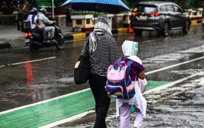 <p><strong>RAINY MONDAY.</strong> A woman and a child share an umbrella under pouring rain in this undated photo. The southwest monsoon (habagat) will bring rain showers across Luzon on Monday (July 29, 2024), the weather bureau said. <em>(PNA photo by Joan Bondoc)</em></p>