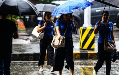 <p><strong>WET WEATHER.</strong> Pedestrians armed with umbrellas cross the street under light rain showers in this undated photo. The low pressure area and the southwest monsoon or habagat will bring rains over most parts of the country, the weather bureau said Tuesday (July 16, 2024).<em> (PNA photo by Joan Bondoc)</em></p>