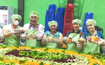 <p><strong>HEALTHY FOOD</strong>. La Trinidad Mayor Romeo Salda (2nd from left) leads the serving of the green vegetable salad as part of the 6th Highland Vegetable Industry Week on Thursday (July 11, 2024) at the La Trinidad Gymnasium. Municipal Agriculturist Nida Organo (5th from left) said the event aims to encourage the public to consume produce grown in La Trinidad and the Cordillera region. <em>(PNA photo courtesy of Denver Dennis Bastingo)</em></p>