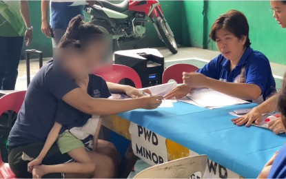 <p><strong>CASH AID.</strong> A woman with her PWD child signs the payroll for the grant of monthly cash aid from the Manila City government in this undated photo. Mayor Honey Lacuna on Thursday (July 11, 2024) said an additional 53,000 members of the vulnerable sector in Manila are set to get their monthly allowances under the social amelioration program of the city government this month.<em> (Photo courtesy of Manila Mayor Honey Lacuna Facebook page)</em></p>