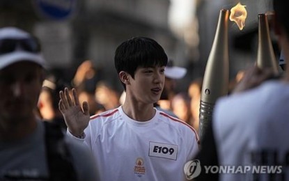 <p>BTS' Jin carries the Paris Olympics torch near the Louvre Museum in Paris on July 14, 2024, in this AP photo. <em>(Yonhap)</em></p>