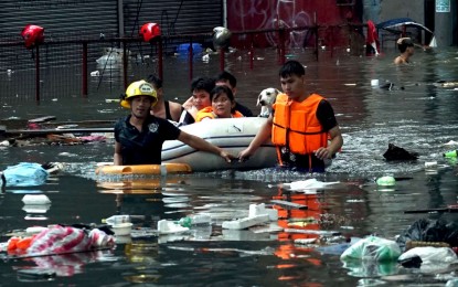 <p><strong>SUBMERGED.</strong> Rescuers assist residents along Araneta Avenue in Quezon City during the onslaught of the southwest monsoon enhanced by Typhoon Carina in July 2024. The QC government on Wednesday (Oct. 2, 2024) urged its 142 barangays to help strengthen its flood mitigation efforts under the “Tanggal Bara, Iwas Baha” program. <em>(PNA file photo by Ben Briones)</em></p>