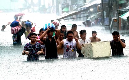 <p><strong>TIME TO EVACUATE.</strong> Residents of Barangay Sto. Domingo in Florentino Street, Quezon City head for a designated evacuation center as heavy rains triggered waist-deep floods in the village on Wednesday (July 24, 2024). Metro Manila has been placed under a state of calamity due to massive flooding caused by continuous heavy rains brought by the Typhoon Carina-enhanced southwest monsoon. <em>(PNA photo by Ben Briones)</em></p>