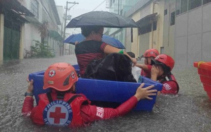 <p><strong>RESCUE OPS</strong>. Philippine Red Cross (PRC) volunteers assist flood victims during the onslaught of habagat intensified by Super Typhoon Carina on July 24, 2024. The Singapore Red Cross has pledged USD50,000 (roughly PHP2.9 million) to the PRC to support its emergency operations. <em>(Photo courtesy of PRC)</em></p>