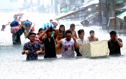 <p><strong>TIME TO EVACUATE.</strong> Residents head to a designated evacuation center as heavy rains caused waist-deep floods in Barangay Sto. Domingo, Quezon City on July 24, 2024. ACT-CIS Party-list Rep. Erwin Tulfo on Tuesday (July 30) called on PhilHealth to step up and cover the costs of medical treatment for leptospirosis and tetanus of disaster victims.<em> (PNA photo by Ben Briones)</em></p>