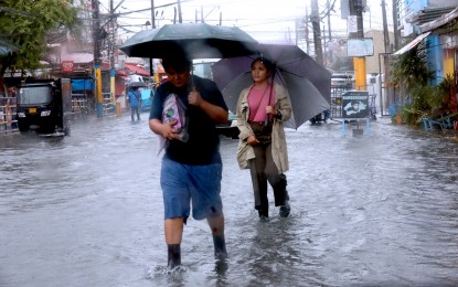 <p><strong>LIFE GOES ON.</strong> Pedestrians wade through flooded streets in Bacoor City, Cavite province on July 23, 2024. The estimated damage to agriculture and infrastructure due to the effects of the southwest monsoon and Typhoons Butchoy and Carina have reached over PHP6.3 billion, the National Disaster Risk Reduction and Management Council reported Thursday (Aug. 8, 2024). <em>(PNA photo by Avito Dalan)</em></p>