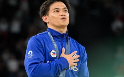 <p><strong>WINNING MOMENT.</strong> Carlos Yulo sings the Philippine national anthem during the awarding ceremony for the vault final event in gymnastics in the 2024 Paris Olympics late Sunday (Aug. 4, 2024 - Manila Time) at the Bercy Arena -- his second gold medal in the ongoing Summer Games. In a social media post, President Ferdinand R. Marcos Jr. congratulated Yulo, who became the first Filipino to win multiple gold medals in a single Olympics. <em>(Photo from International Gymnastics Federation Facebook)</em></p>