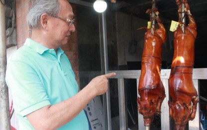 <p><strong>ASF-FREE LECHON</strong>. Ramon Ferreros, founder of the La Loma Lechoneros Association in Quezon City, checks out his products on Sunday (Aug. 25, 2024). He assured buyers that all roasted pigs being sold by their group are free from African swine fever<em>. (PNA photo by Pot Chavez)</em></p>