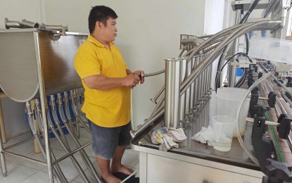 <p><strong>MECHANIZED BOTTLING.</strong> A worker refills bottles of Virgin Coconut Oil through automated bottling equipment in this undated photo. The Department of Trade and Industry in Negros Oriental turned over the PHP1.1 million mechanized equipment to the Barangay Liptong Small Farmers Association in Valencia, Negros Oriental last month under its Shared Services Facility program. <em>(Photo courtesy of BLISCOFA)</em></p>