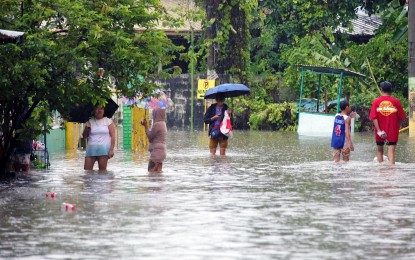 <p><strong>KNEE-DEEP.</strong> Residents wade through a flooded village in Bacoor, Cavite on Monday (Sept. 2, 2024). Permanent government employees affected by calamities are eligible to apply for a five-day special emergency leave, the Civil Service Commission said Friday (Sept. 6, 2024). <em>(PNA photo by Avito Dalan)</em></p>