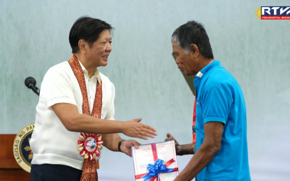 <p><strong>CONDONED.</strong> An agrarian reform beneficiary receives his Certificate of Condonation with Release of Mortgage (COCRoM) from President Ferdinand R. Marcos Jr. on Friday (Sept. 13, 2024) in Palanan City, Nueva Ecija. At least 6,000 ARBs were relieved from paying their debts and obligations on agricultural lands awarded under the agrarian reform program. <em>(Photo screengrab from RTVM Facebook page)</em></p>