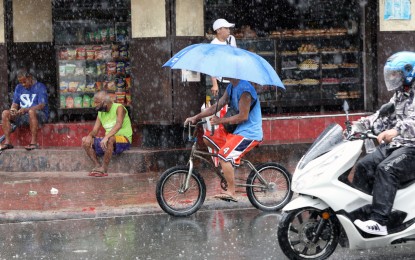 <p><strong>RAINY RIDE.</strong> This cyclist protects himself from the rain using an umbrella while riding a bike along Abad Santos Avenue in Manila on Sept. 18, 2024. The southwest monsoon or “habagat” affecting Luzon and the Visayas will continue to bring rains over a large part of the country, the weather bureau said Friday (Sept. 20). <em>(PNA photo by Yancy Lim)</em></p>