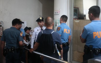 <p><strong>ARRESTED.</strong> Police collar a former immigration employee (hidden) who entered the DOJ compound with a handgun Tuesday night (Sept. 24, 2024). The suspect will be initially charged with illegal possession pending the final disposition of other possible charges. <em>(PNA photo by Ben Pulta)</em></p>