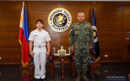 <p><strong>SERVICE TO COUNTRY.</strong> Petty Officer 1st Class Carlos Edriel Yulo (left) and Naval Reserve Command chief Marine Maj. Gen. Joseph Ferrous Cuison during Yulo's oath-taking rites at the PN headquarters at Naval Station Jose Andrada, Roxas Boulevard in Manila on Tuesday (Oct. 1, 2024). The Olympic gold medalist joined the PN Reserve Force and was given the rank of Petty Officer 1st Class. <em>(Photo courtesy of the Philippine Navy)</em></p>