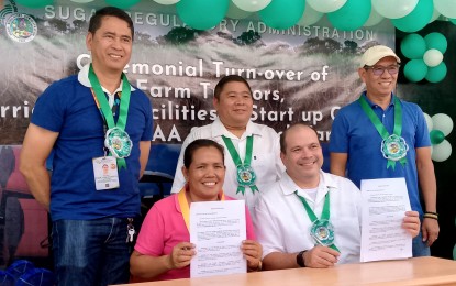 <p><strong>COLLABORATION.</strong> Department Agriculture-Negros Island Region OIC-Regional Executive Director Jose Albert Barrogo (standing, left) witnesses the signing of the deed of donation between the Sugar Regulatory Administration Administrator Pablo Luis Azcona (seated, right) and a farmers’ cooperative representative during the turnover of farm tractors, irrigation facilities, and start-up capital to 13 block farms in Negros Island at the SRA office in Bacolod City on Oct. 4, 2024. Also present were SRA Board Member David Andrew Sanson (standing, center) and Deputy Administrator II Ignacio Santillana. (<em>PNA photo by Nanette L. Guadalquiver</em>)</p>