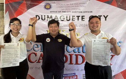 <p><strong>ENDORSEMENT.</strong> Incumbent Dumaguete City Mayor Felipe Antonio Remollo (center) raises the hands of Karissa Faye Maxino and his son, Felipe Claudio Remollo, during the filing of certificates of candidacy in Negros Oriental province on Monday (Oct. 7, 2024). Felipe Remollo is running for Dumaguete mayor with Maxino as running mate. (<em>PNA photo by Mary Judaline Flores Partlow)</em></p>