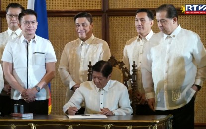 <p><strong>STRONG DEFENSE POSTURE.</strong> President Ferdinand R. Marcos Jr. signs the Self-Reliant Defense Posture Revitalization Law in a ceremony in Malacañang on Tuesday (Oct. 8, 2024). The new law, a priority legislation of the Marcos administration, aims to develop the country’s defense industry by creating ways to boost the local production of defense equipment. <em>(RTVM Screengrab)</em></p>