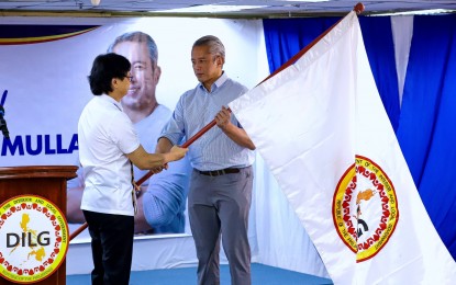 <p><strong>NEW DILG CHIEF.</strong> Secretary Jonvic Remulla (right) receives the flag of the Department of the Interior and Local Government (DILG) from his predecessor Benjamin Abalos Jr. during turnover rites at the agency's main office in Quezon City on Wednesday (Oct. 9, 2024). Remulla said he would push for a new law mandating structural reforms in the Philippine National Police (PNP). <em>(PNA photo by Robert Oswald Alfiler)</em></p>