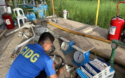 <p><strong>ILLEGAL.</strong> A member of the Criminal Investigation and Detection Group (CIDG) makes an inventory of pieces of evidence seized from an illegal LPG refilling station in Barangay Sto. Angel Norte, Sta. Cruz, Laguna on Monday (Oct. 14, 2024). CIDG operatives seized PHP7 million worth of illegal LPG tanks and refilling equipment during the operation. <em>(Photo courtesy of CIDG)</em></p>