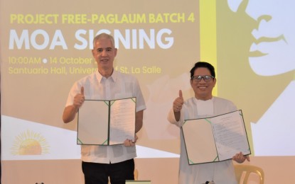 <p><strong>PARTNERSHIP</strong>. Negros Occidental Governor Eugenio Jose Lacson (left) and Br. Joaquin Severino Martinez, president and chancellor of the University of St. La Salle, show the memorandum of agreement for the Project FREE or Flagships to Reach Educational Excellence-Paglaum Program Batch 4 signed at Santuario de La Salle in Bacolod City on Monday (Oct. 14, 2024). The program’s latest edition offers post-graduate scholarships for up to 600 public school teachers in the province starting Nov. 16. <em>(Photo courtesy of PIO Negros Occidental)</em></p>