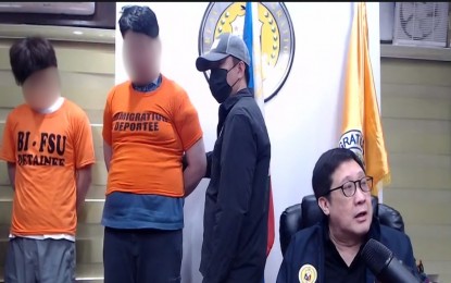 <p>Bureau of Immigration Commissioner Joel Viado (right) presents re-arrested South Korean estafa suspect Na Ikhyeon and his cohort, Kang Changbeom. <em>(Screenshot from BI video)</em></p>