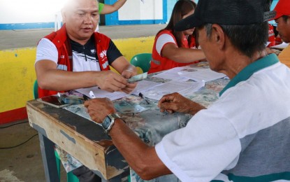 A partner-beneficiary in Sipalay City, Negros Occidental, receives a compensation of PHP9,600 for completing the 20-day cash-for-work activities under the Department of Social Welfare and Development Risk Resiliency Program - Climate Change Adaptation and Mitigation.