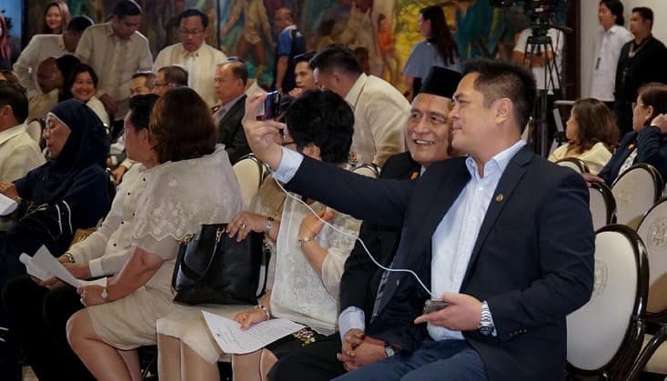 PCOO chief Martin Andanar snaps a photo with his father, special envoy to Malaysia Wencelito Andanar during the latter's oath-taking ceremony in Sept. 12, 2018.